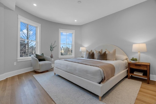 bedroom with light hardwood / wood-style floors and multiple windows