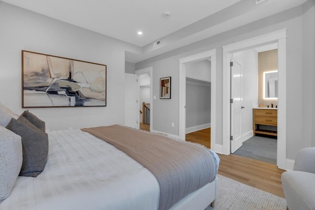 bedroom featuring a walk in closet, light wood-type flooring, and a closet