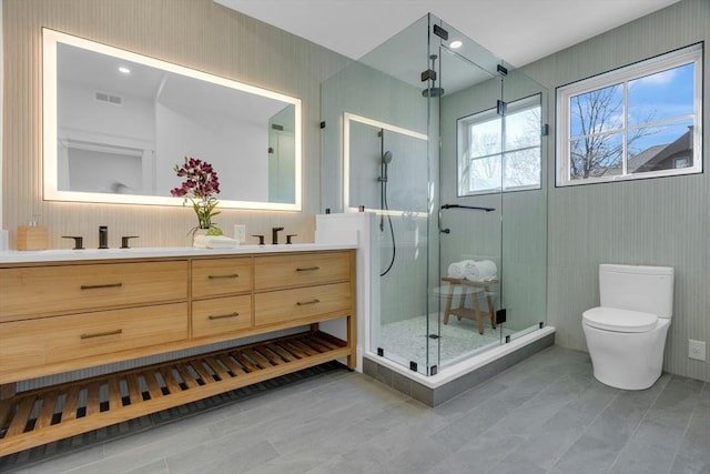 bathroom featuring toilet, vanity, and a shower with shower door