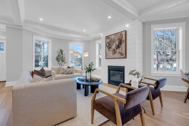 living room with beam ceiling, a healthy amount of sunlight, a large fireplace, and ornamental molding