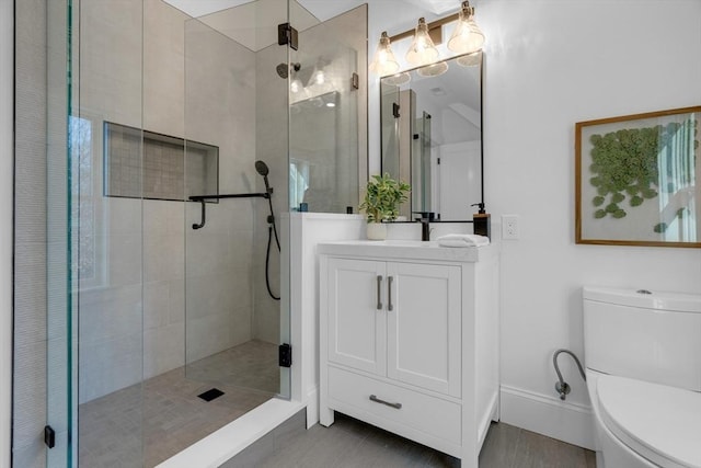 bathroom featuring toilet, a shower with shower door, and vanity