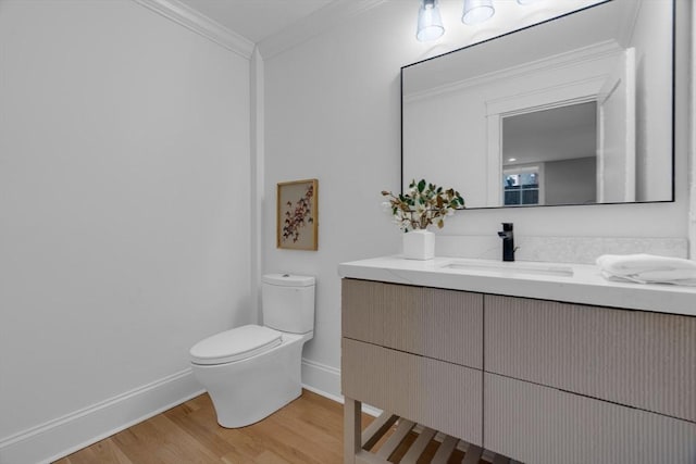 bathroom featuring toilet, vanity, crown molding, and hardwood / wood-style flooring