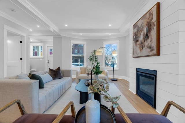 living room with beam ceiling, ornamental molding, and light wood-type flooring