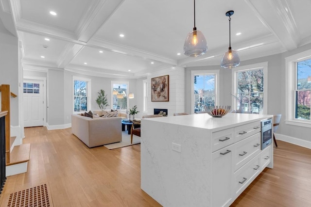 kitchen featuring a kitchen island, white cabinetry, beamed ceiling, plenty of natural light, and hanging light fixtures