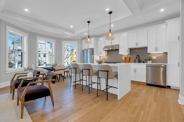 kitchen featuring beamed ceiling, appliances with stainless steel finishes, hanging light fixtures, and a center island