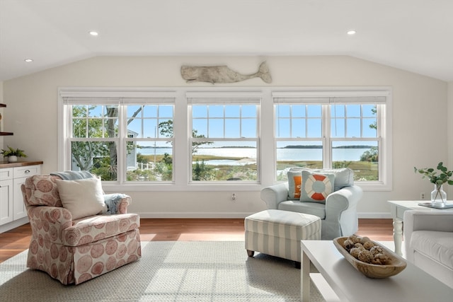 sunroom with lofted ceiling and a water view