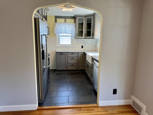 167 Pleasant St, East Longmeadow, MA 01028 - kitchen featuring a sink, arched walkways, baseboards, and gray cabinets