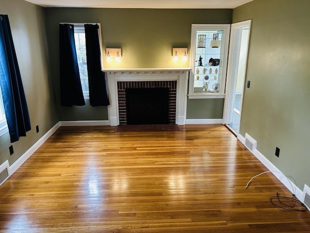 167 Pleasant St, East Longmeadow, MA 01028 - unfurnished living room featuring wood-type flooring, a brick fireplace, and baseboards