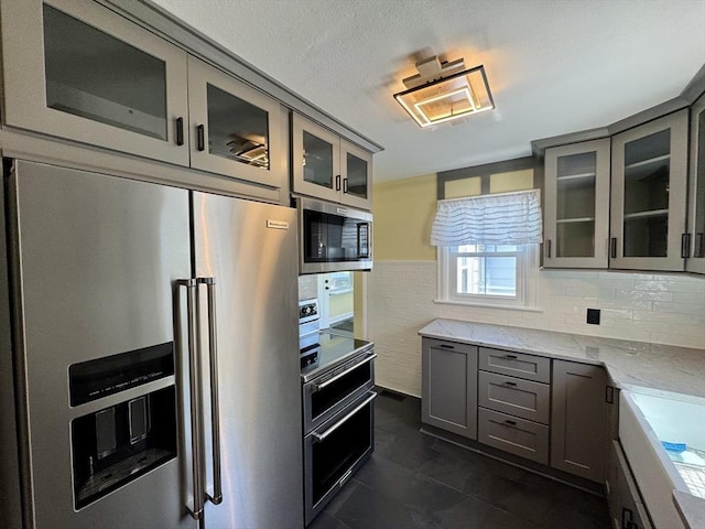 167 Pleasant St, East Longmeadow, MA 01028 - kitchen featuring appliances with stainless steel finishes, gray cabinets, light stone countertops, glass insert cabinets, and a textured ceiling