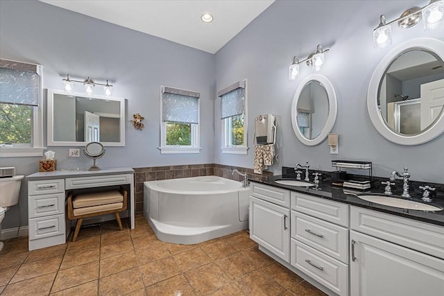bathroom featuring double vanity, a sink, a bath, and toilet