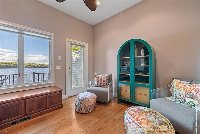 sitting room with baseboards, ceiling fan, visible vents, and light wood-style flooring