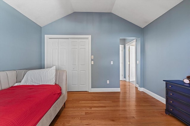 bedroom featuring a closet, baseboards, vaulted ceiling, and wood finished floors