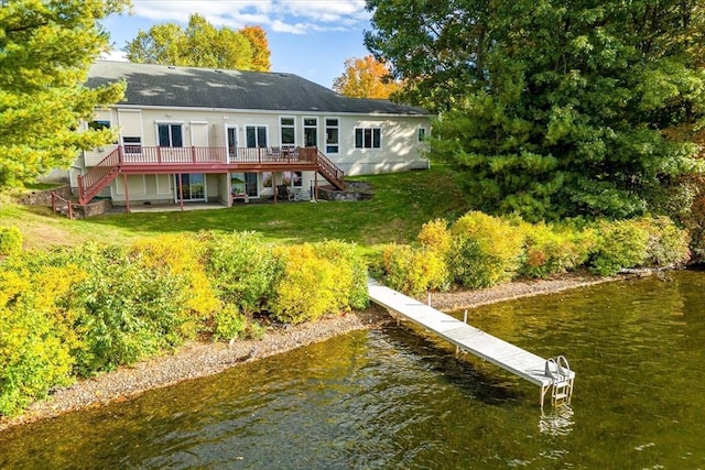 rear view of property with stairway, a yard, and a deck with water view