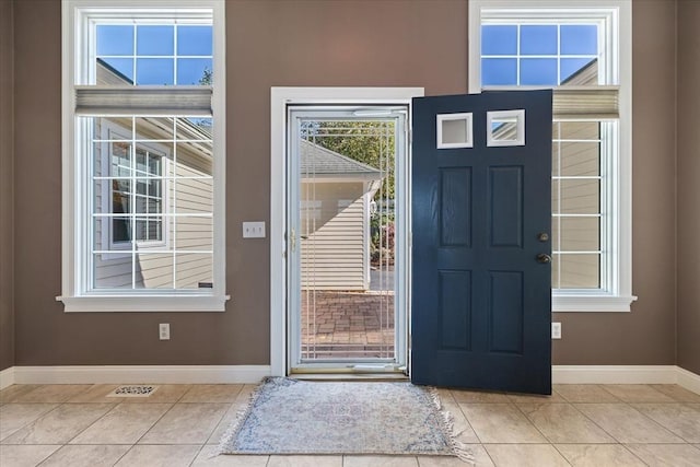 foyer entrance featuring baseboards, visible vents, and light tile patterned floors