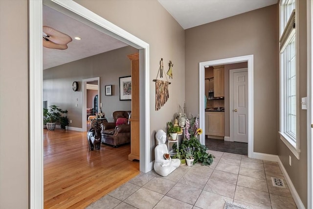 hallway with baseboards, light tile patterned floors, and visible vents