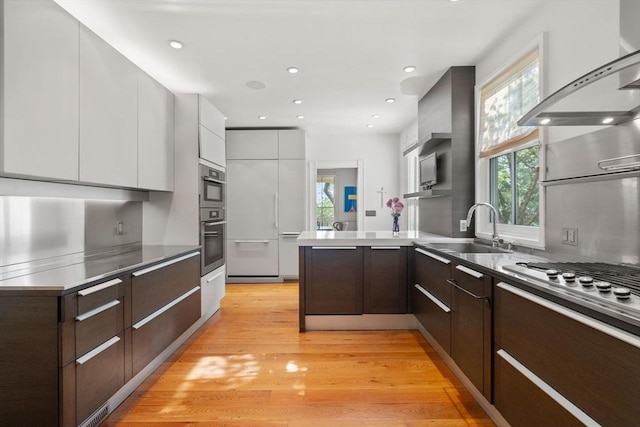 kitchen with modern cabinets, a sink, a peninsula, white cabinets, and dark brown cabinetry