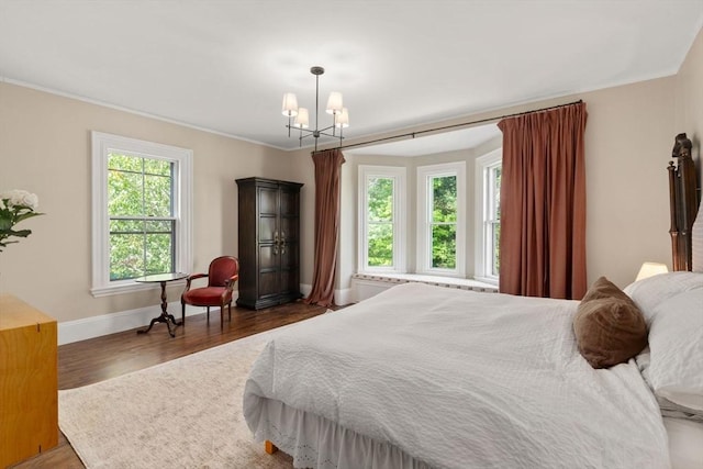 bedroom with baseboards, wood finished floors, a chandelier, and ornamental molding