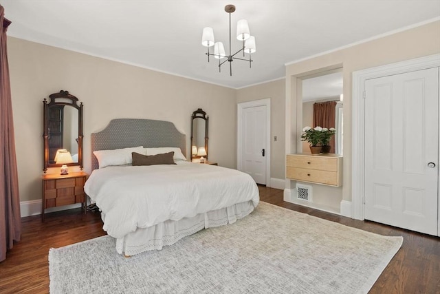bedroom with dark wood finished floors, a chandelier, ornamental molding, and baseboards