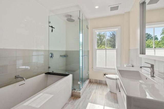 bathroom featuring healthy amount of natural light, a stall shower, toilet, and a freestanding tub