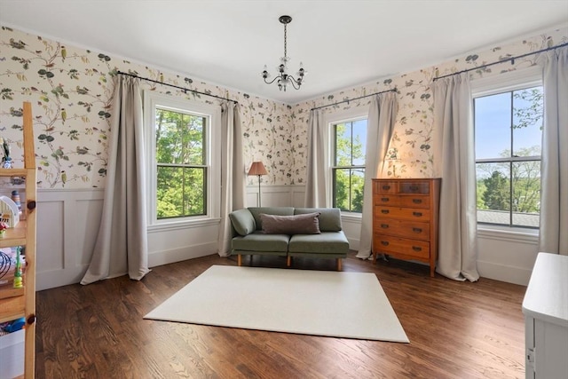 sitting room with wainscoting, wallpapered walls, plenty of natural light, dark wood-style floors, and a chandelier