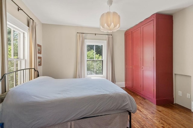 bedroom featuring multiple windows, light wood-style flooring, and baseboards
