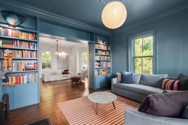 living area featuring ornamental molding, built in shelves, healthy amount of natural light, and wood finished floors