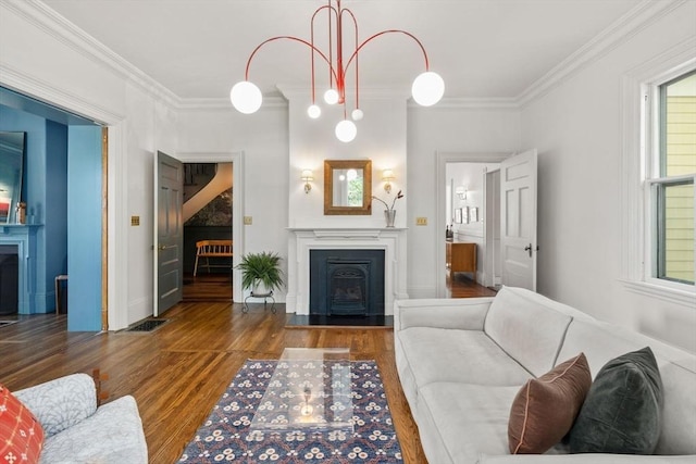 living area featuring a fireplace, crown molding, wood finished floors, and baseboards