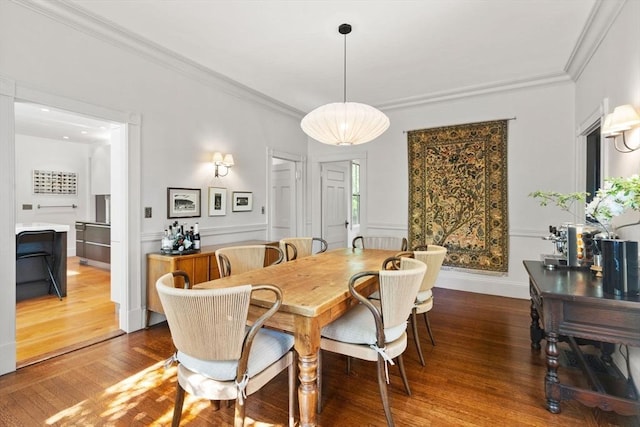 dining area featuring wood finished floors and crown molding