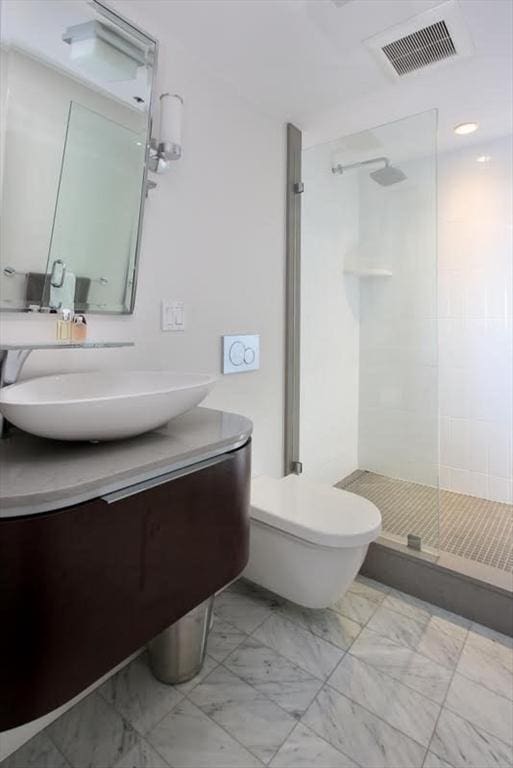 bathroom featuring a stall shower, marble finish floors, vanity, and toilet