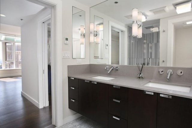 bathroom with baseboards, wood finished floors, and double vanity