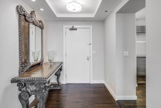 foyer with wood finished floors, a raised ceiling, baseboards, and recessed lighting