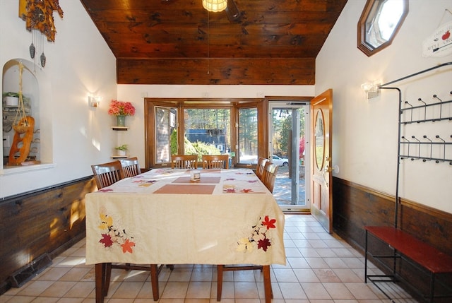 dining room with light tile patterned floors, wooden walls, and wood ceiling