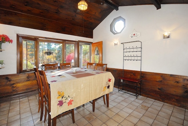 tiled dining area with high vaulted ceiling, beam ceiling, wood ceiling, and wooden walls