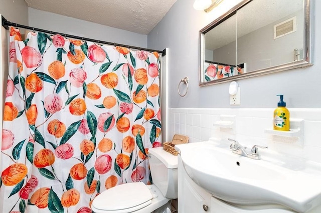 bathroom with a textured ceiling, tile walls, a shower with curtain, toilet, and vanity