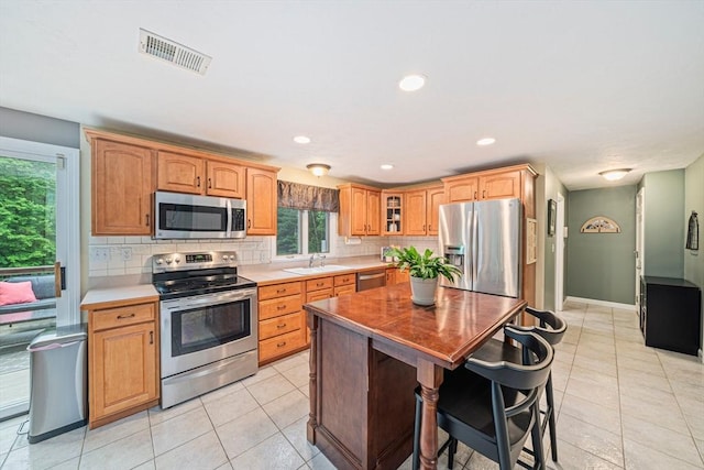 9 Captains Way E, Bridgewater, MA 02333 - kitchen with appliances with stainless steel finishes, tasteful backsplash, light tile patterned floors, glass insert cabinets, and recessed lighting