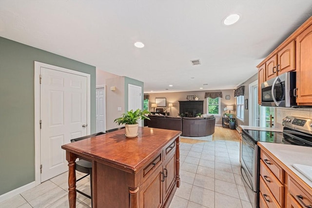 9 Captains Way E, Bridgewater, MA 02333 - kitchen featuring stainless steel appliances, light tile patterned floors, a fireplace, a kitchen island, and a breakfast bar area