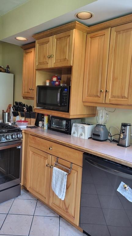 kitchen featuring black appliances, brown cabinetry, light tile patterned flooring, and light countertops