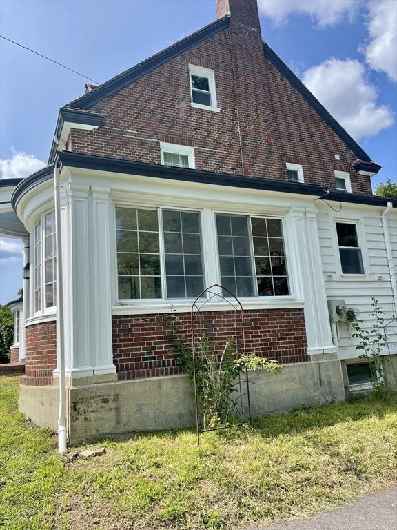 view of side of home with entry steps, a lawn, and brick siding