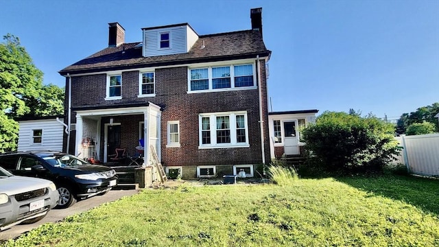 rear view of property featuring entry steps, a chimney, a lawn, and brick siding