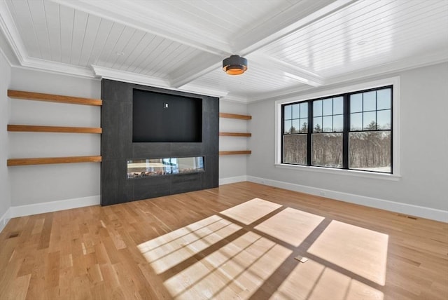 unfurnished living room with beam ceiling, crown molding, a tiled fireplace, and light wood-type flooring