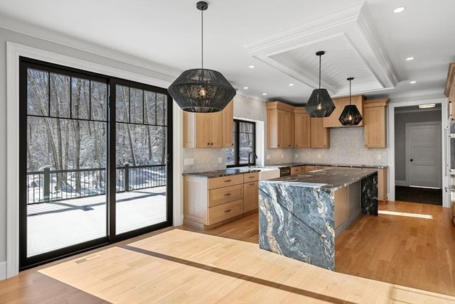 kitchen with a kitchen island, a healthy amount of sunlight, hanging light fixtures, and dark stone countertops