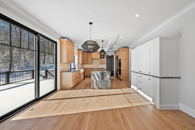 kitchen with light wood-type flooring, light brown cabinetry, pendant lighting, and crown molding