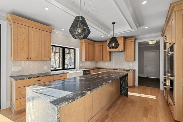 kitchen featuring light hardwood / wood-style floors, dark stone countertops, hanging light fixtures, and ornamental molding