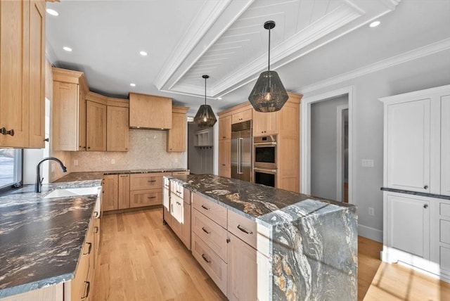 kitchen featuring sink, hanging light fixtures, dark stone counters, and a kitchen island