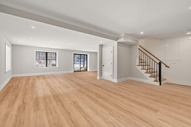 unfurnished living room with ornamental molding and light wood-type flooring