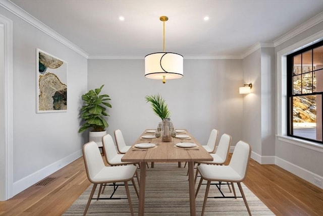 dining space with wood-type flooring and crown molding