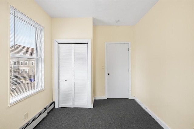 unfurnished bedroom with a closet, dark carpet, and a baseboard radiator