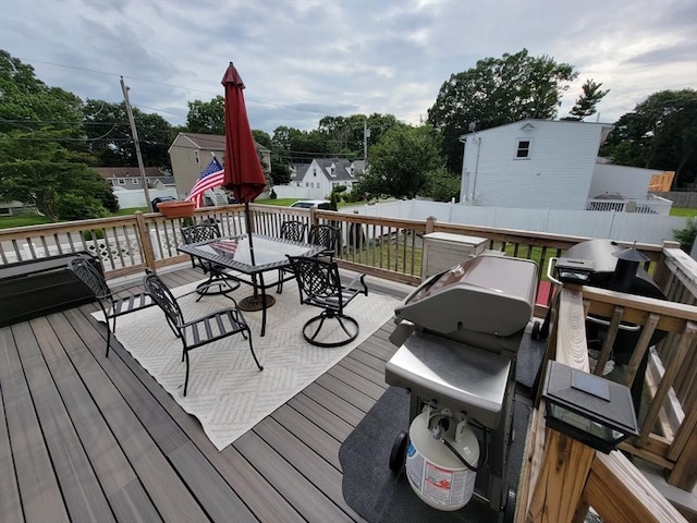 wooden deck featuring a grill, fence, and outdoor dining area