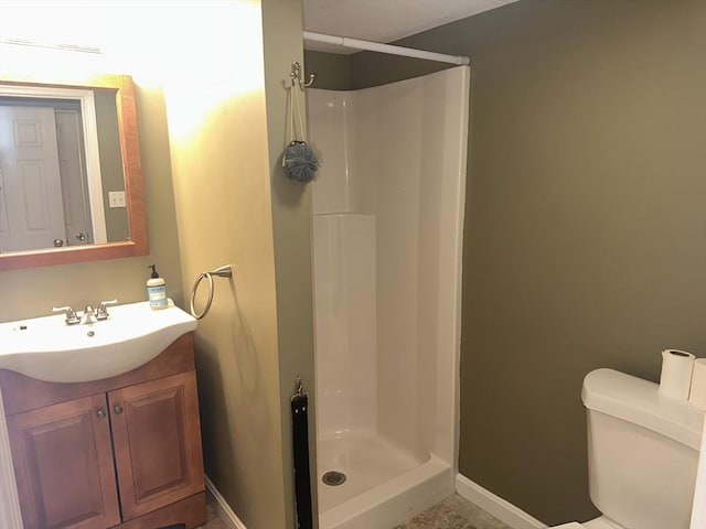 bathroom featuring toilet, a shower stall, baseboards, and vanity