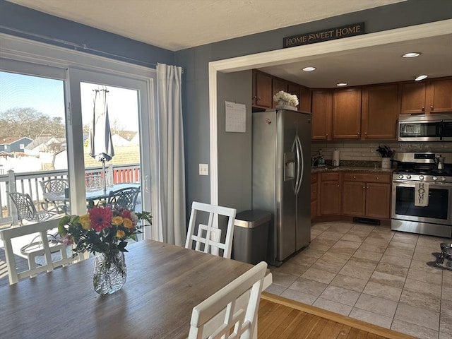 kitchen with light tile patterned floors, recessed lighting, stainless steel appliances, backsplash, and dark countertops